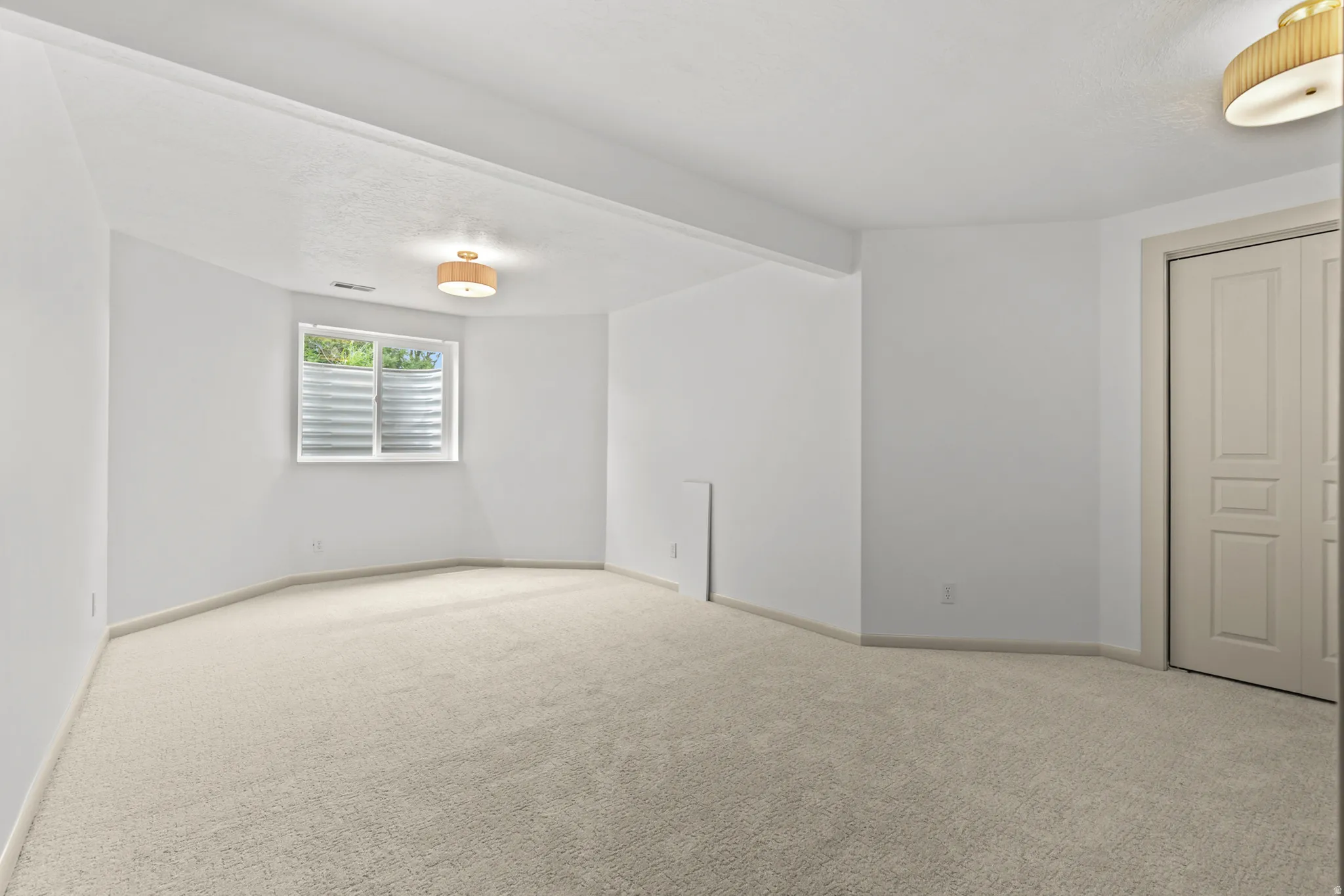 Carpeted room featuring a single window, white walls, and two flush mount light fixtures