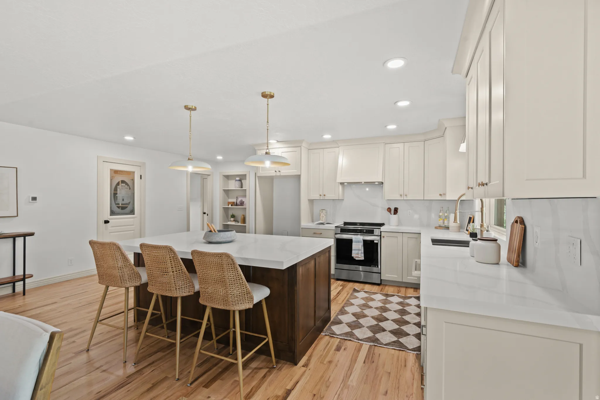 Modern kitchen featuring a large central island with seating, white countertops, light wood-finish flooring, and recessed lighting