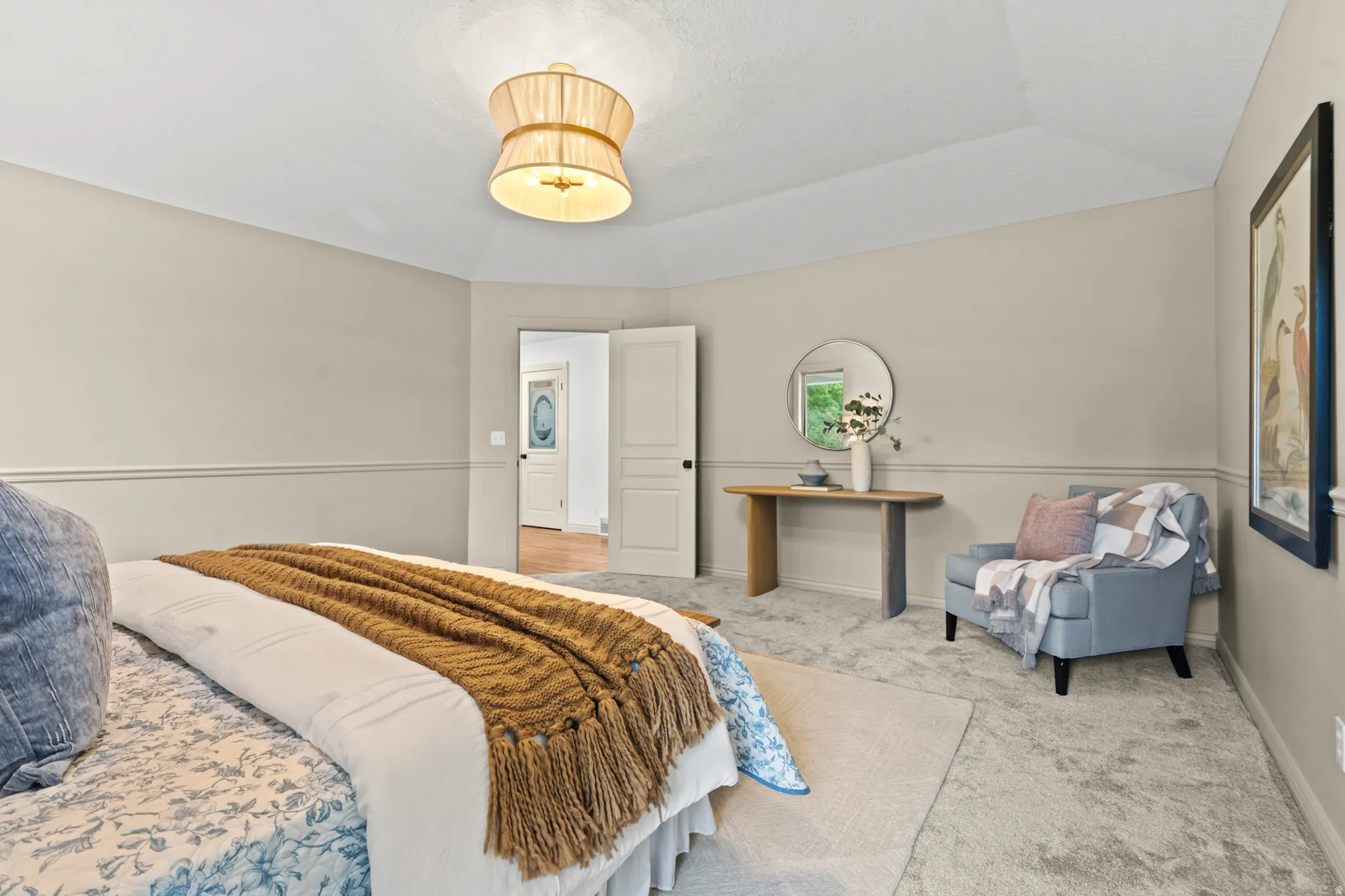Carpeted room featuring a tray ceiling with a drum pendant light fixture, chair rail molding, and a paneled interior door