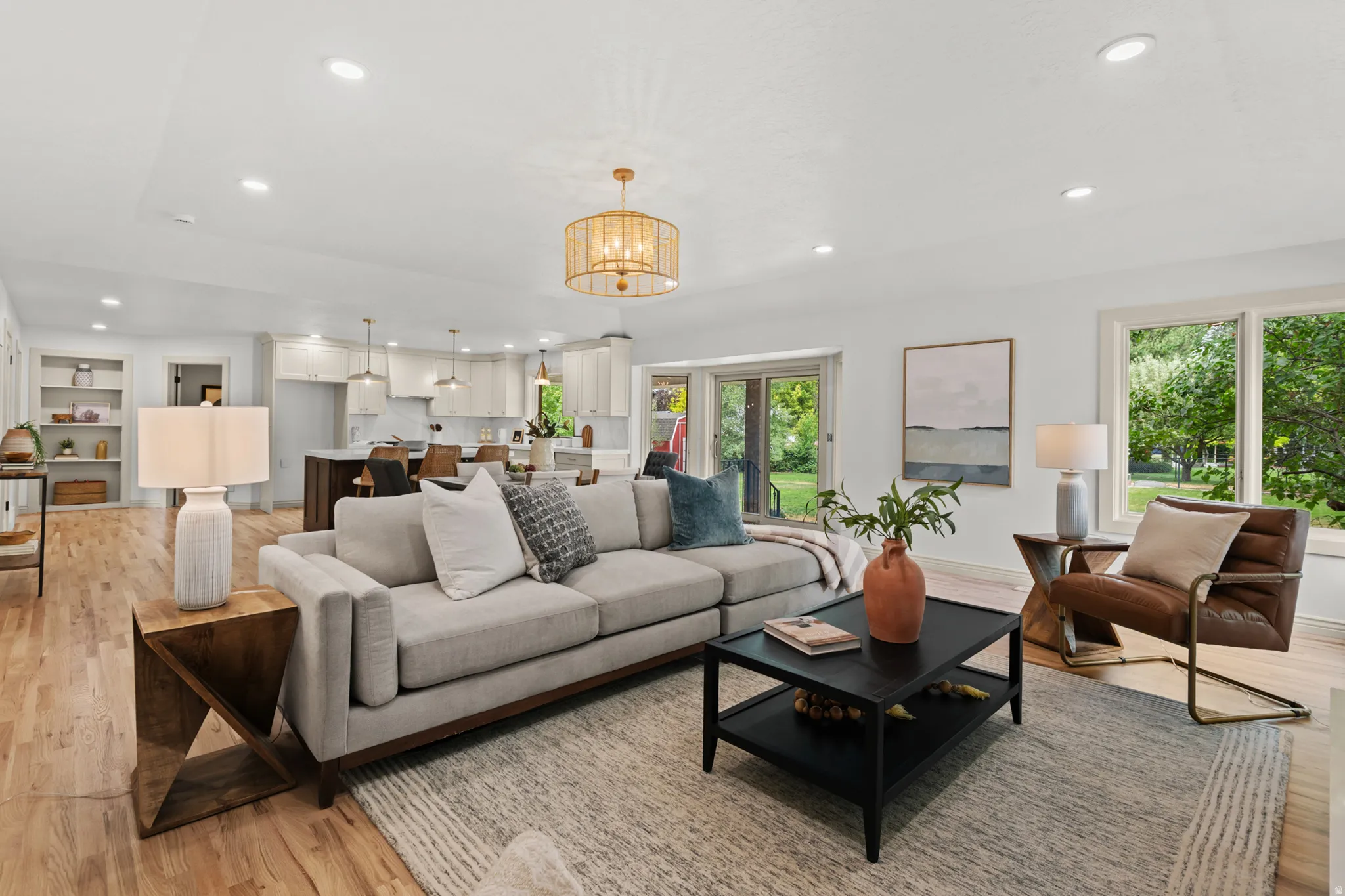 Open-concept living space featuring wood-finish flooring, recessed lighting, and a decorative pendant light fixture