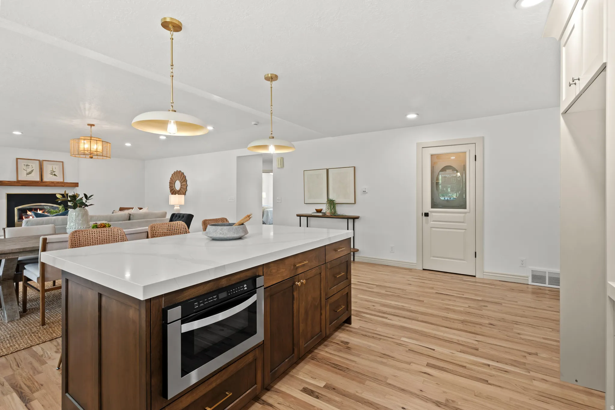 Kitchen island with a white countertop and integrated microwave drawer, complemented by wood flooring