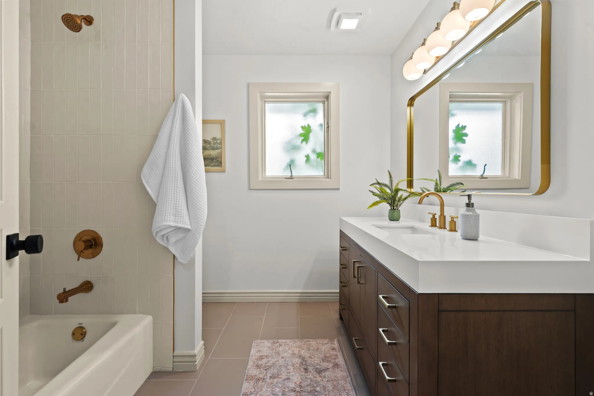 Bathroom featuring a dark wood-finish vanity with a white countertop and gold-tone fixtures
