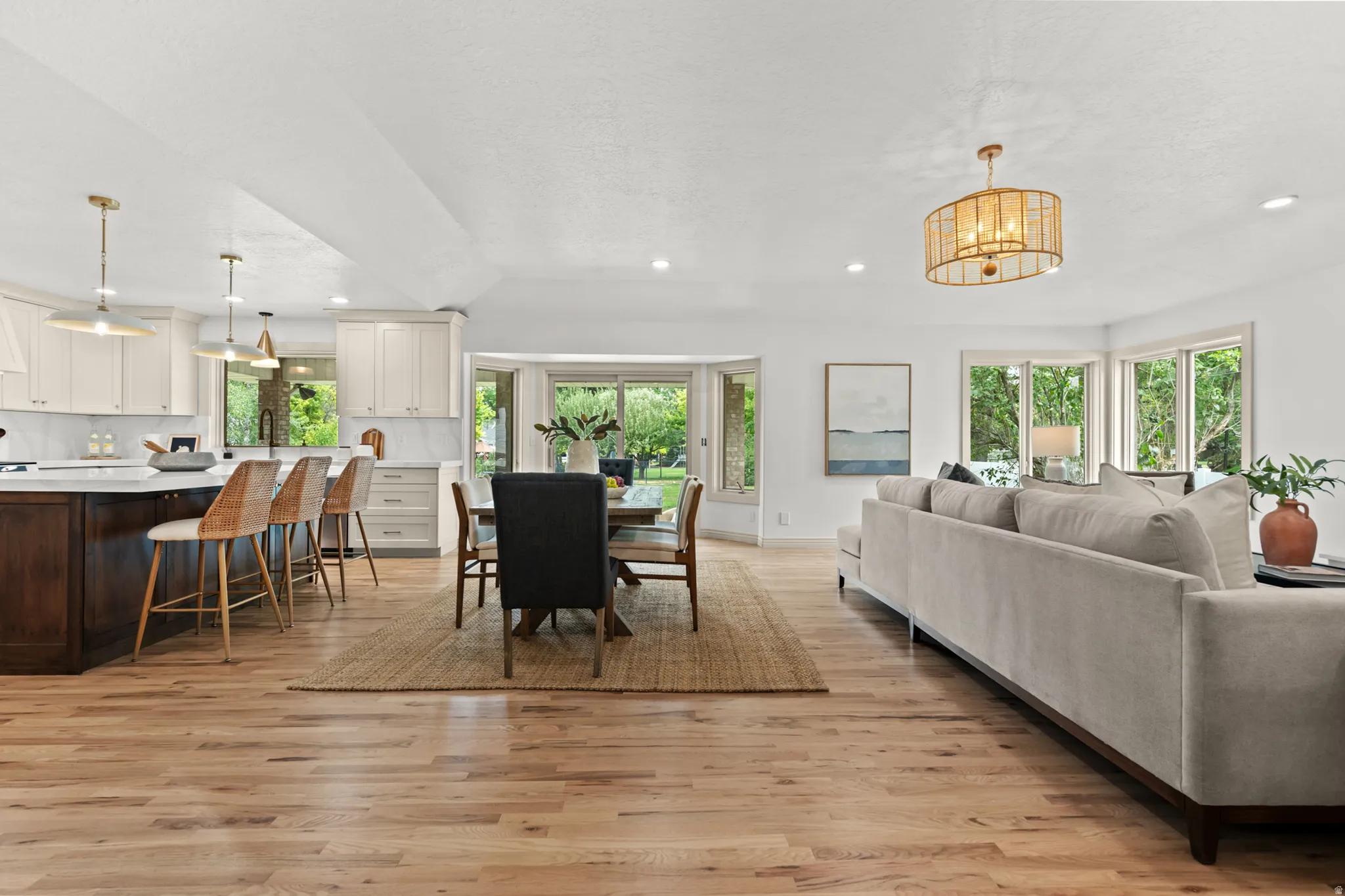 Open-concept living space featuring wood-finish flooring, recessed lighting, and a kitchen island with seating