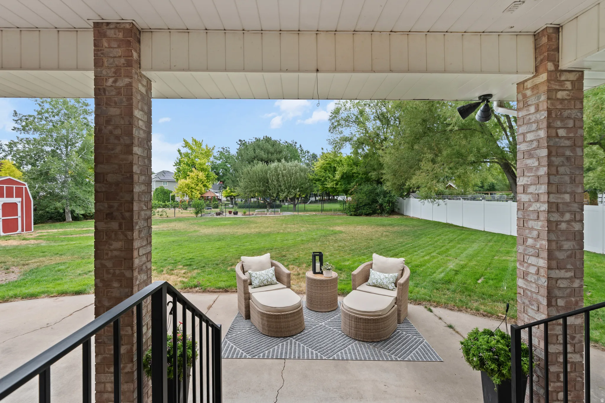 Covered patio featuring brick support columns, a ceiling fan, and concrete flooring