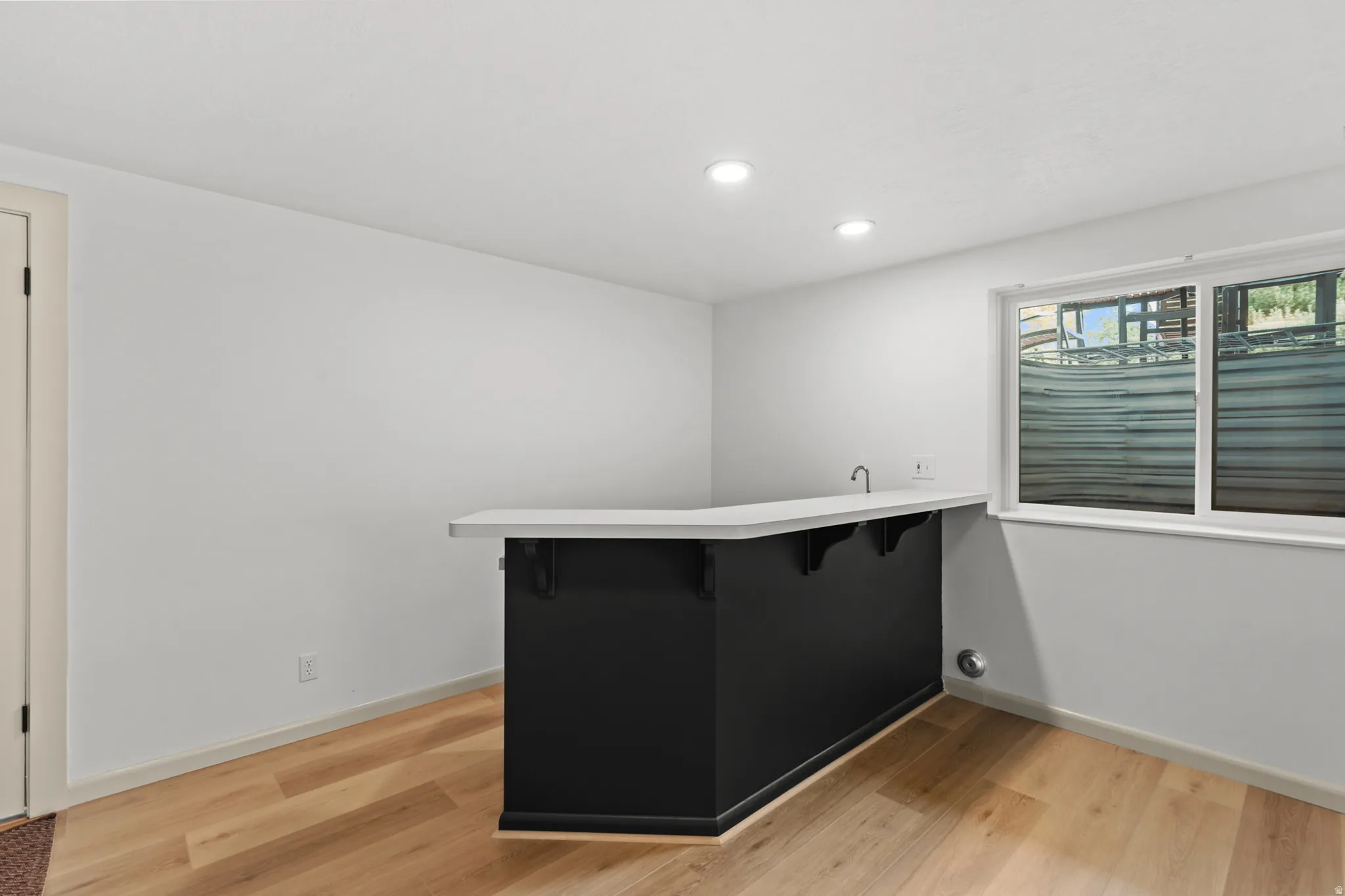 Entertainment space featuring a built-in wet bar with a light-toned countertop and dark cabinetry