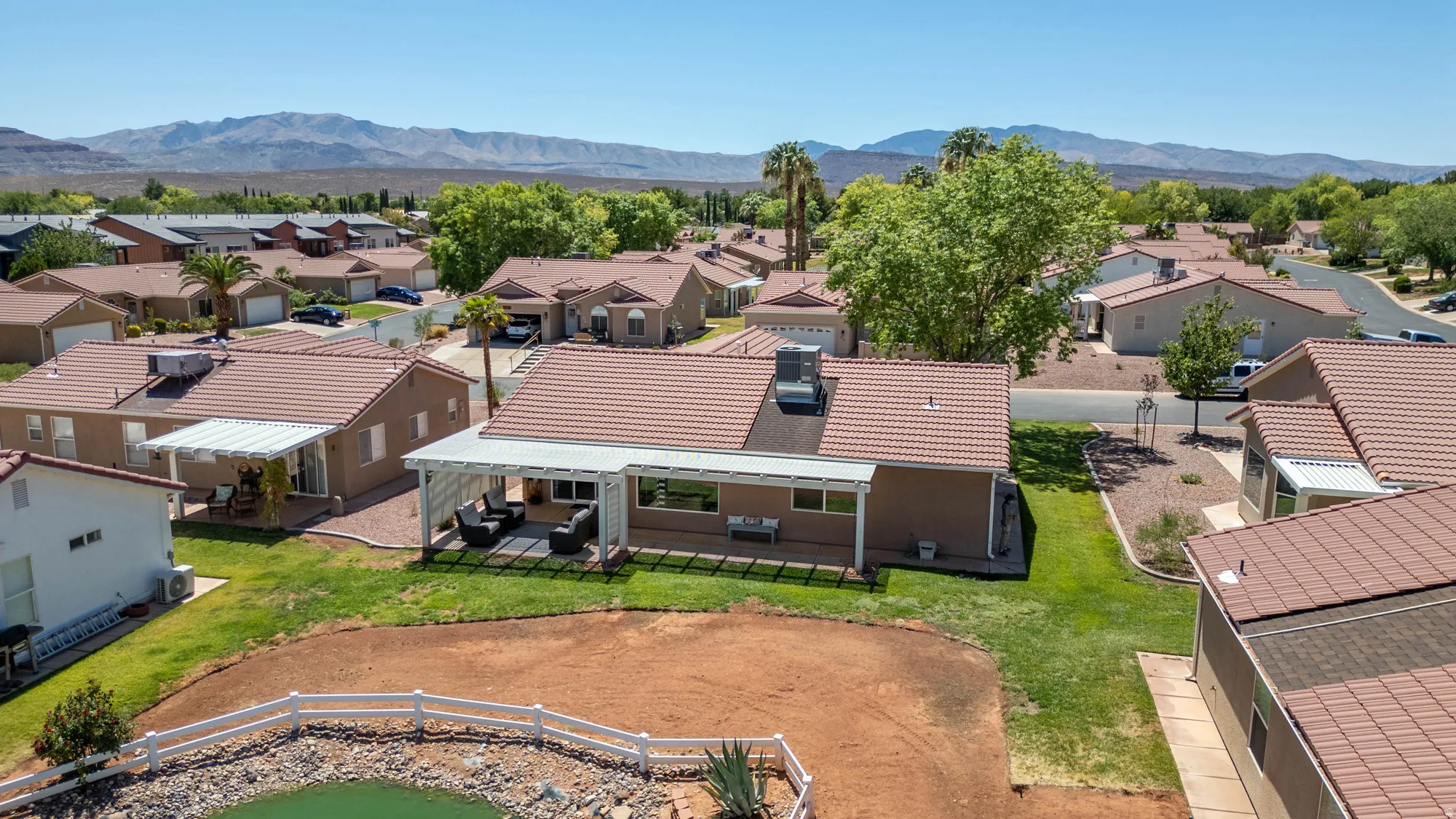 Rear exterior featuring an extended covered patio, tile roofing, and a partial privacy fence