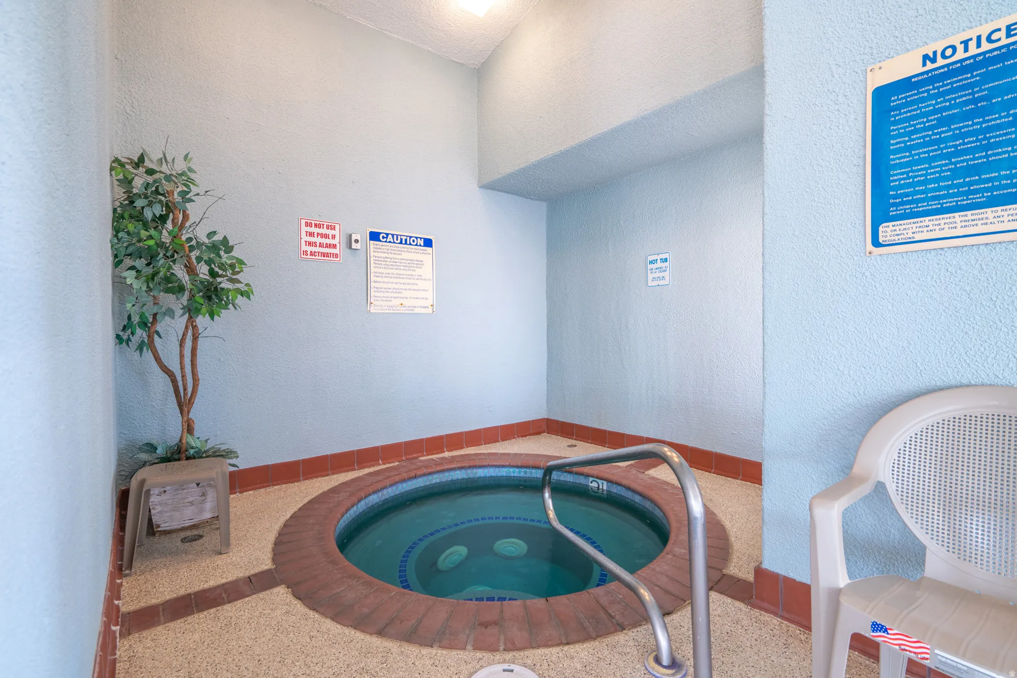 Indoor hot tub featuring a brick surround and a metal grab rail