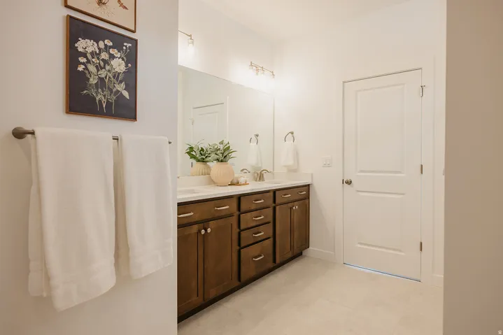 Bathroom featuring a dual vanity with wood-finish cabinetry, light-toned countertop, and undermount sinks