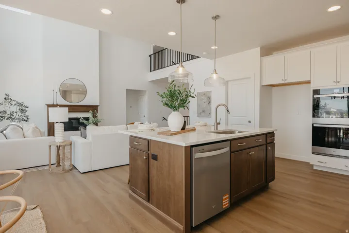 Open-concept living space featuring a central kitchen island with a stainless steel sink and dishwasher