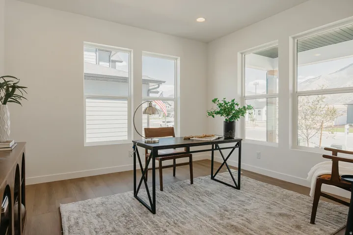 Bright room featuring multiple large windows, wood-finish flooring, recessed lighting, and white baseboards