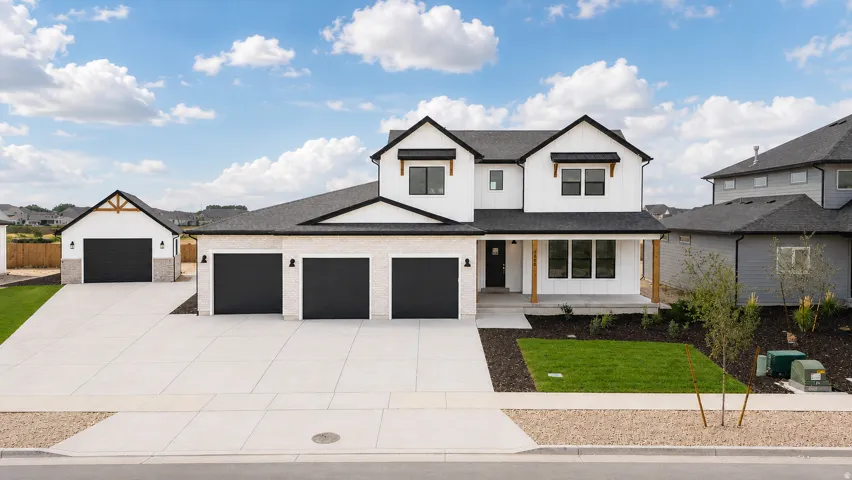 Contemporary residence showcasing white siding with black trim, a three-car attached garage, and an additional detached two-car garage