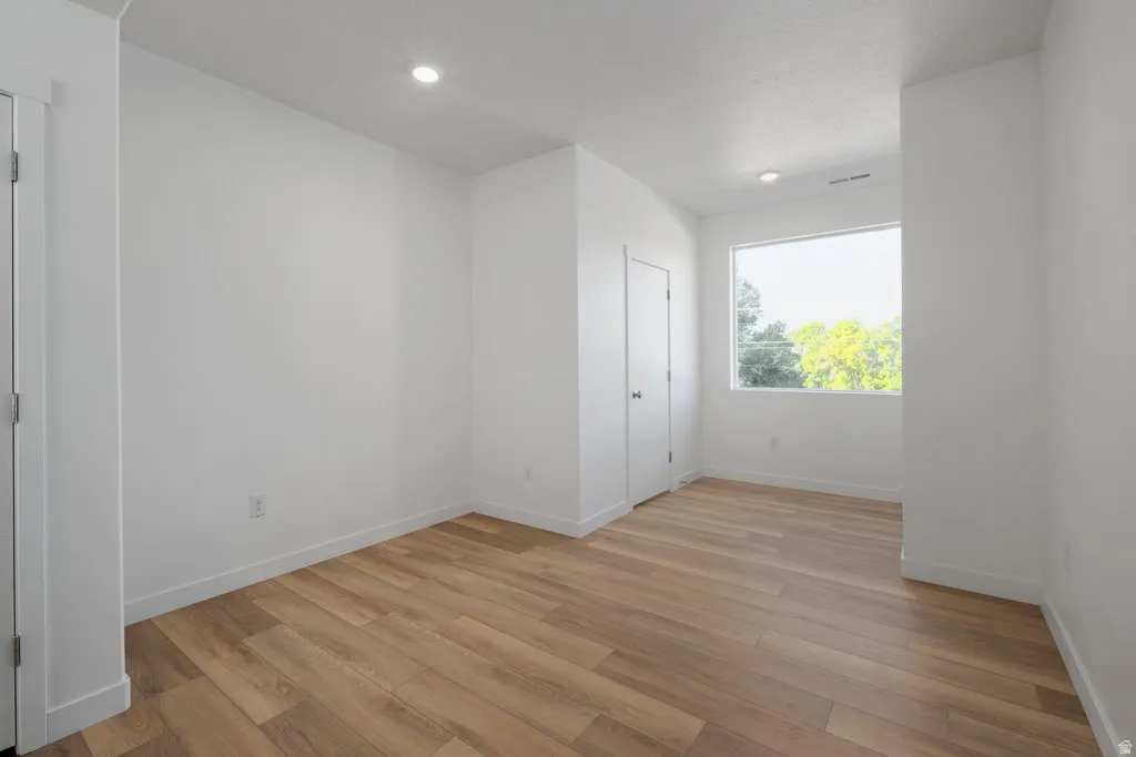 Bright interior space featuring wood-finish flooring, white baseboards, and neutral wall finishes
