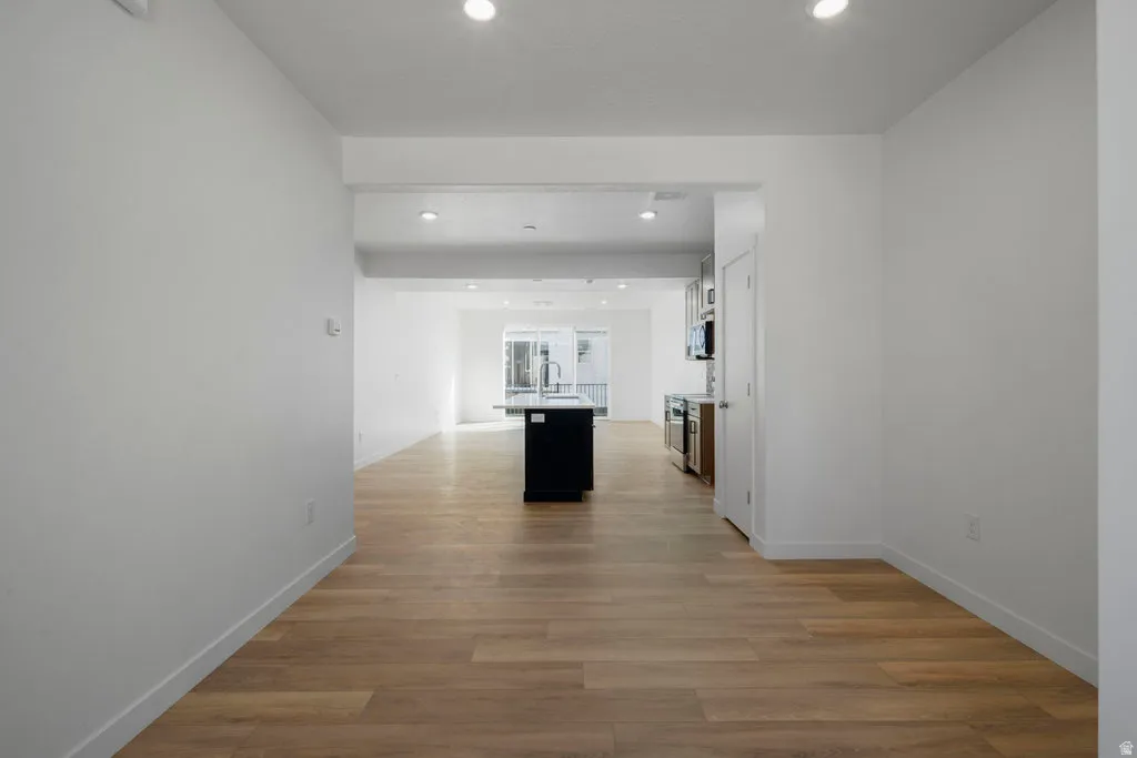 Open-concept interior featuring light wood-finish flooring, recessed lighting, and white walls