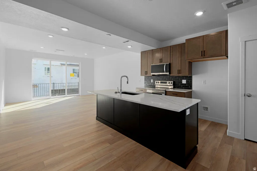 Open-concept living area featuring wood-finish flooring, recessed lighting, and a glass sliding door to a balcony