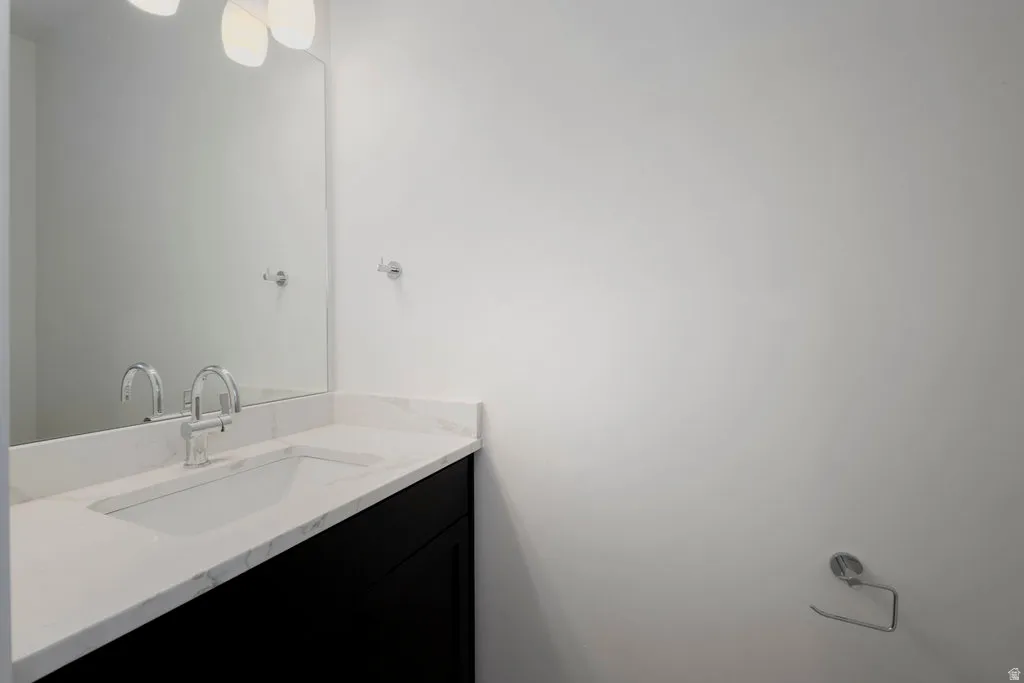 Bathroom vanity with a white countertop, undermount sink, chrome faucet, and a large wall mirror