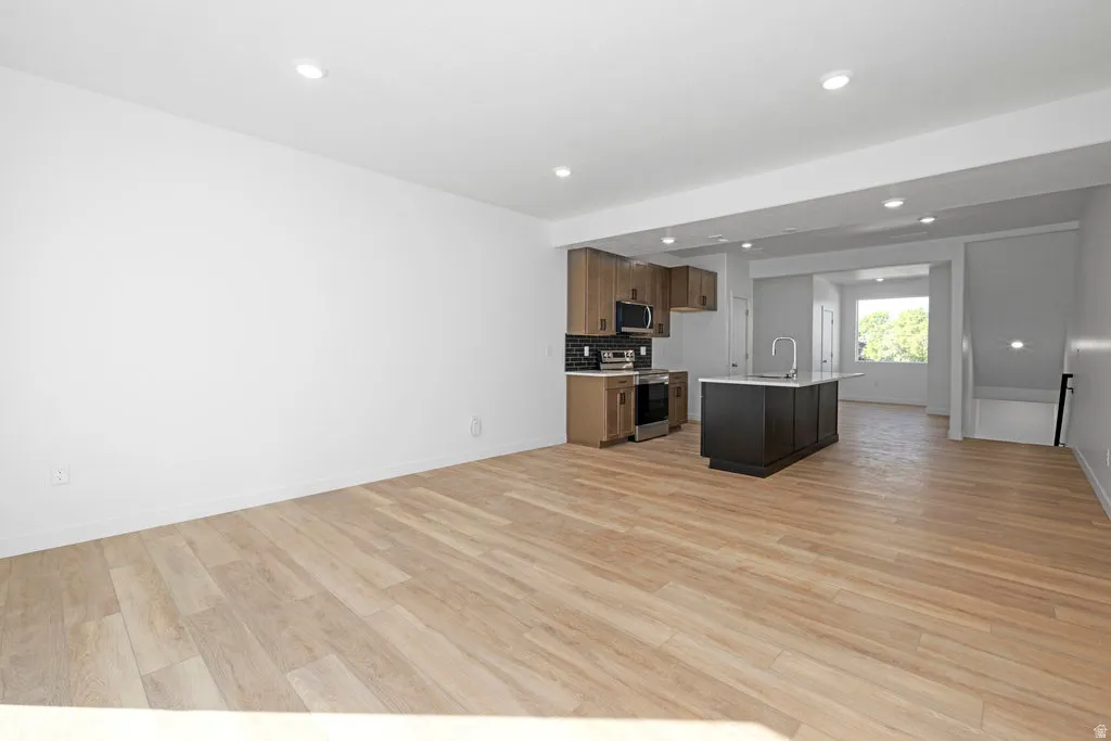 Open-concept living space featuring wood-finish flooring, recessed lighting, and a contemporary kitchen