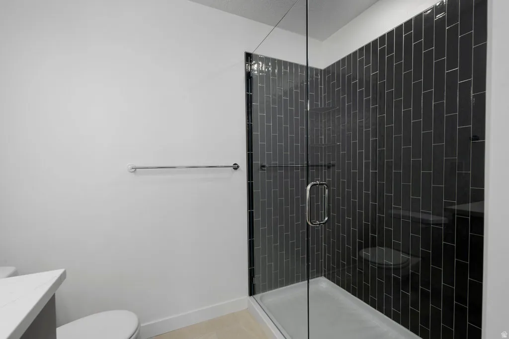 Full-glass shower enclosure with dark vertical subway tile surround, integrated shower bench, and a chrome towel bar