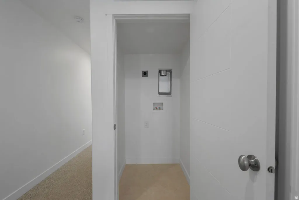 Dedicated laundry closet featuring a recessed utility box, hookups for appliances, and neutral-toned carpeting