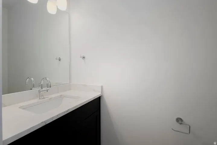 Bathroom vanity with a white countertop, undermount sink, chrome faucet, and a large wall mirror