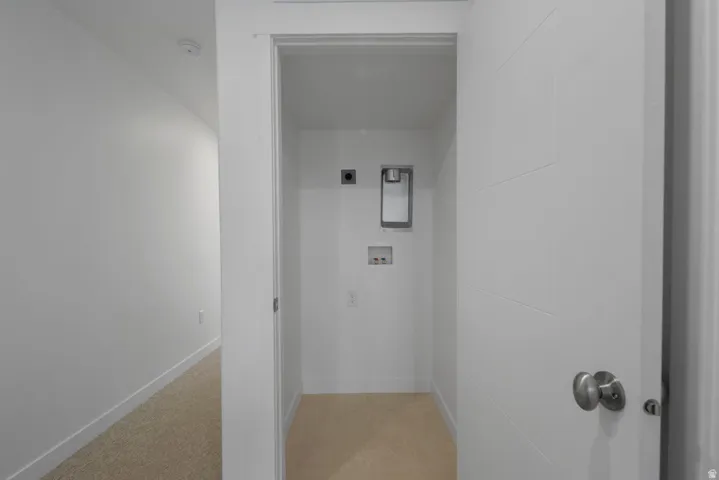 Dedicated laundry closet featuring a recessed utility box, hookups for appliances, and neutral-toned carpeting