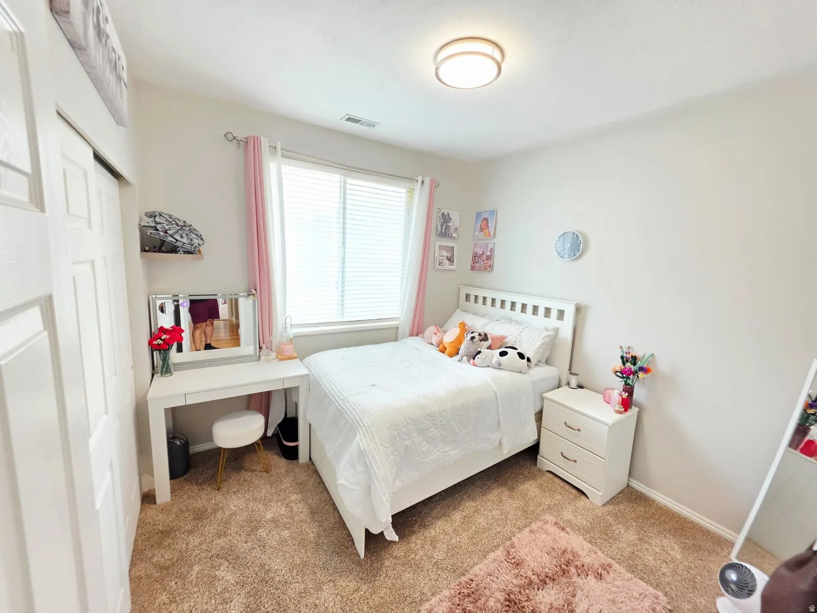 Carpeted bedroom featuring a window with blinds, white paneled closet doors, a built-in flush mount ceiling light, and light-colored walls