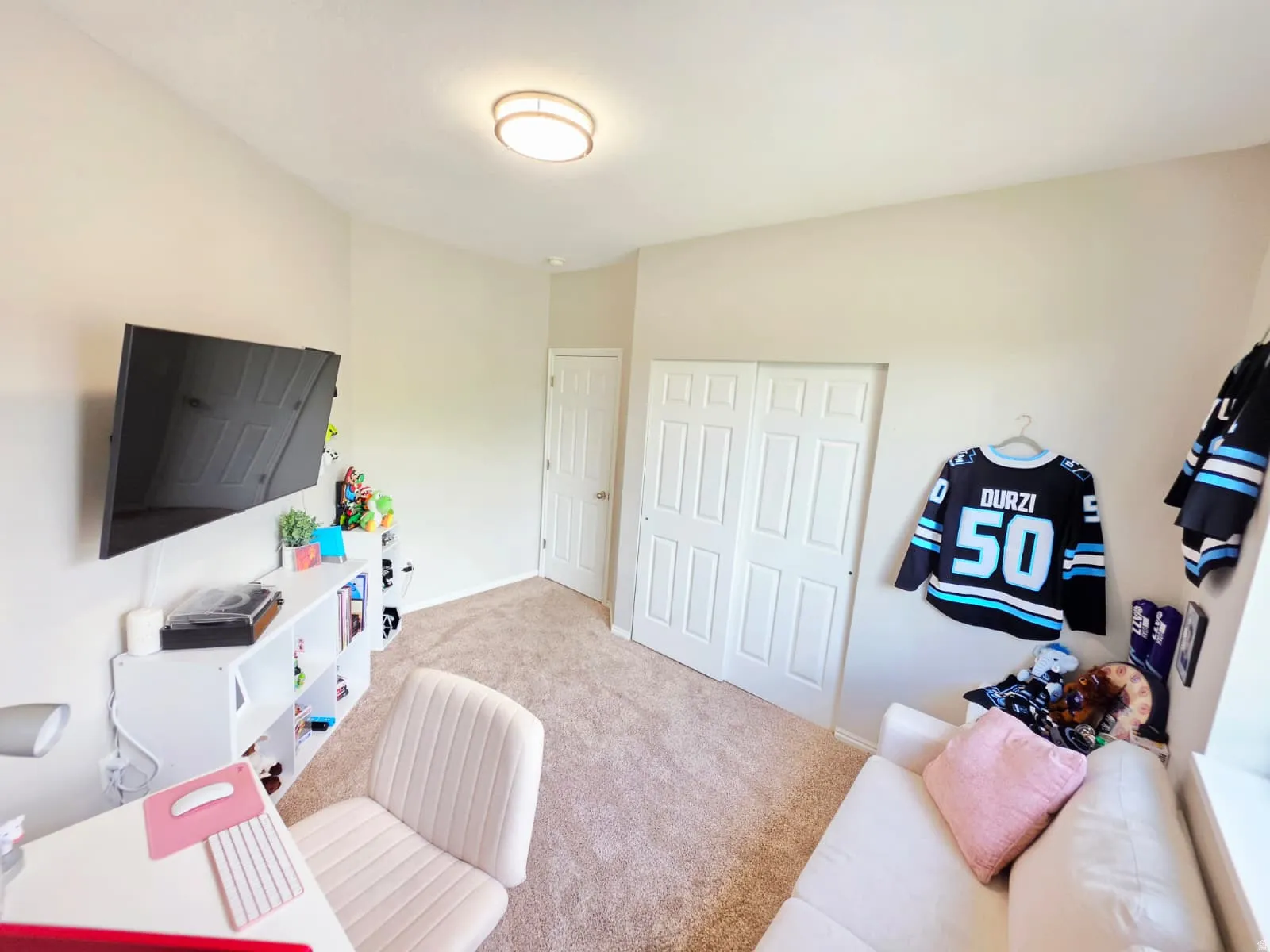 Carpeted room featuring a ceiling-mounted light fixture, white interior door, and bi-fold closet doors