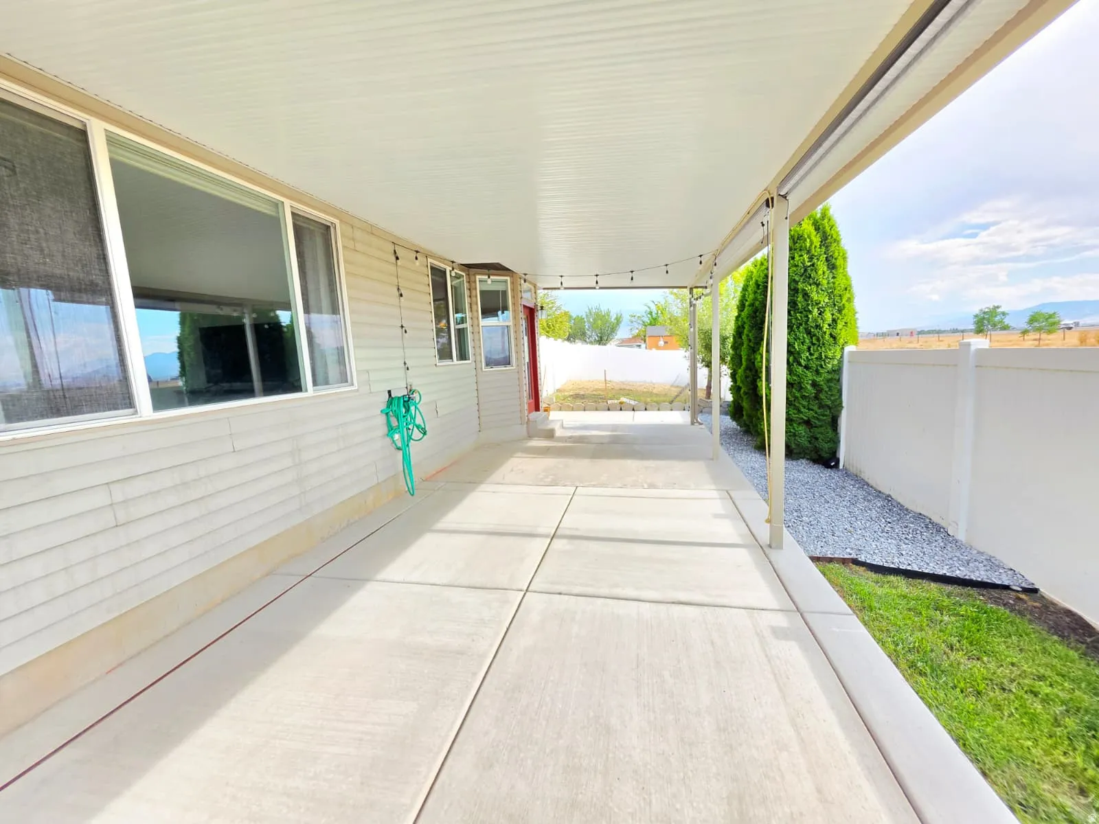 Expansive covered patio featuring a corrugated metal roof, string lighting, and direct access to the interior