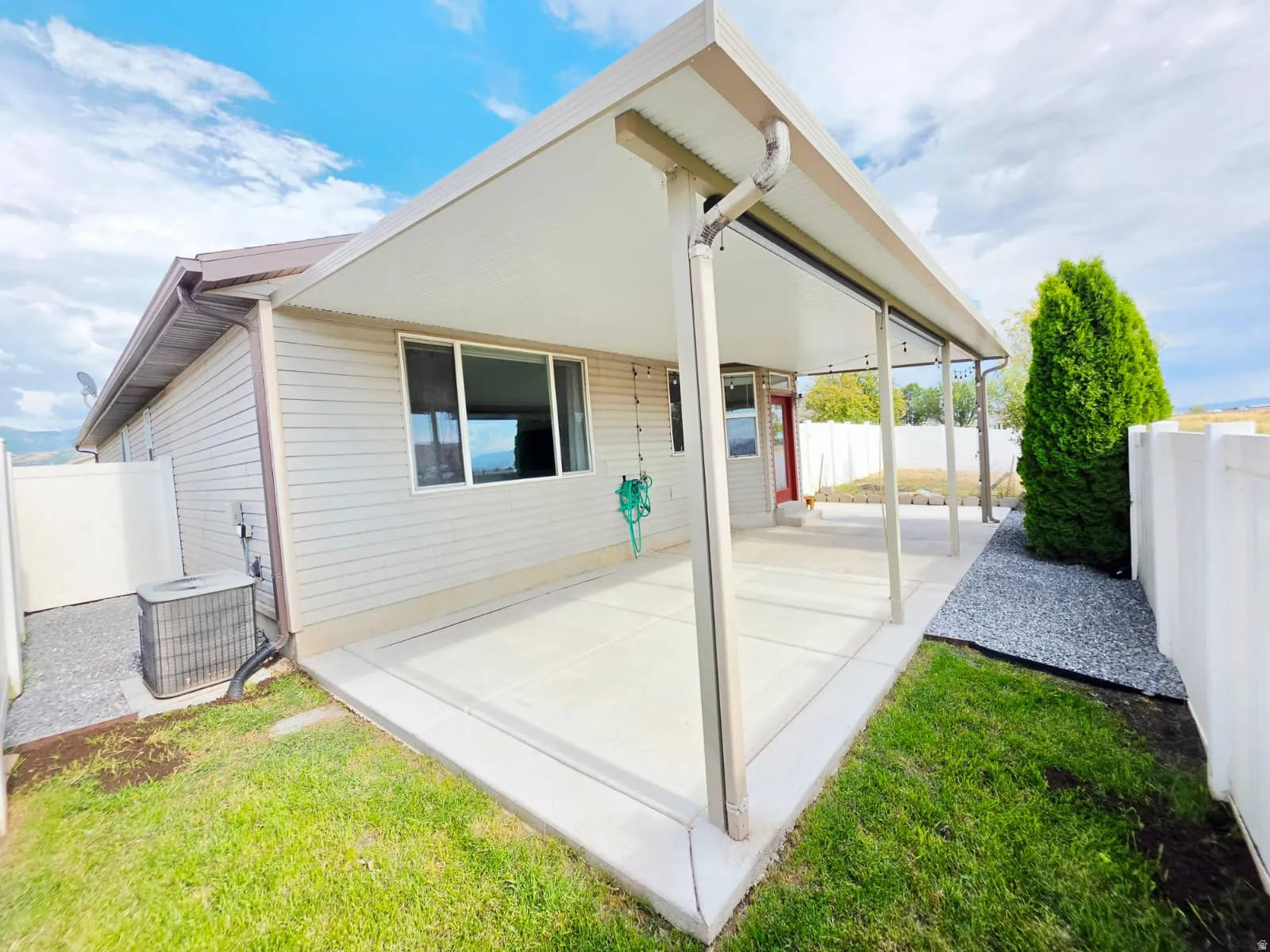 Covered patio with a concrete slab, supported by four columns and featuring vinyl siding