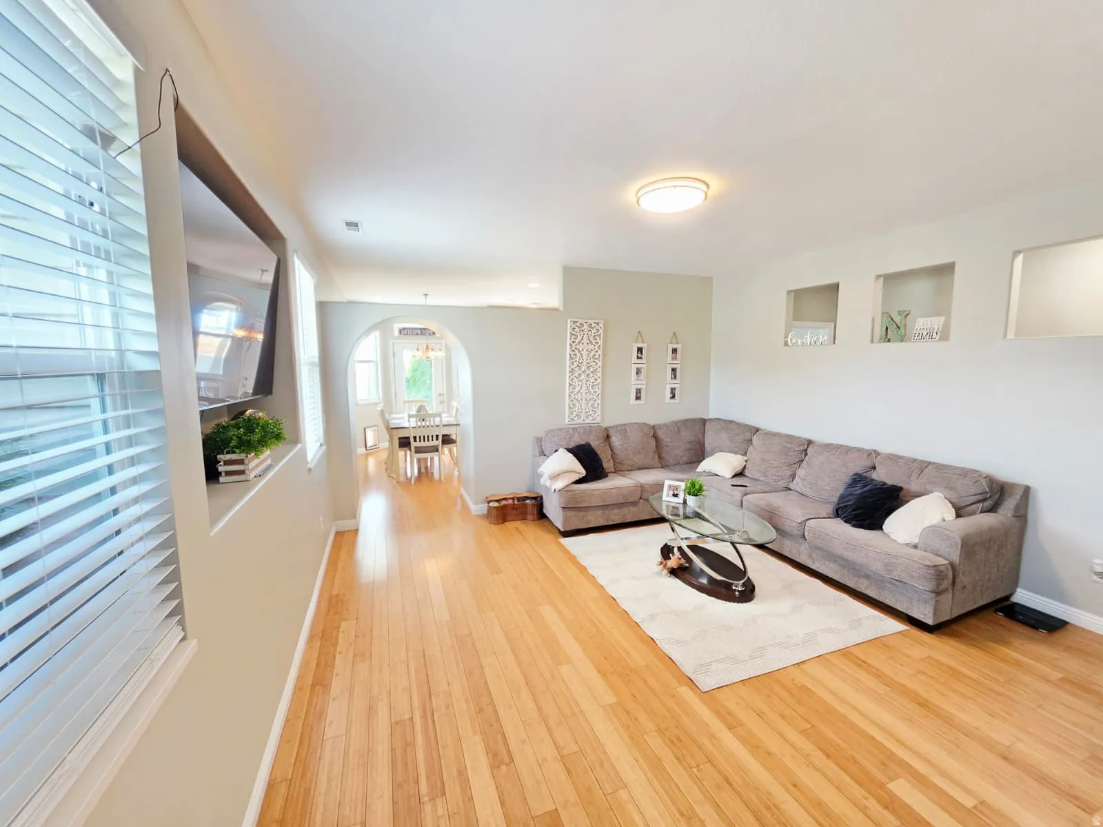 Spacious living area featuring wood-finish flooring, recessed wall niches, and an arched doorway leading to an additional space