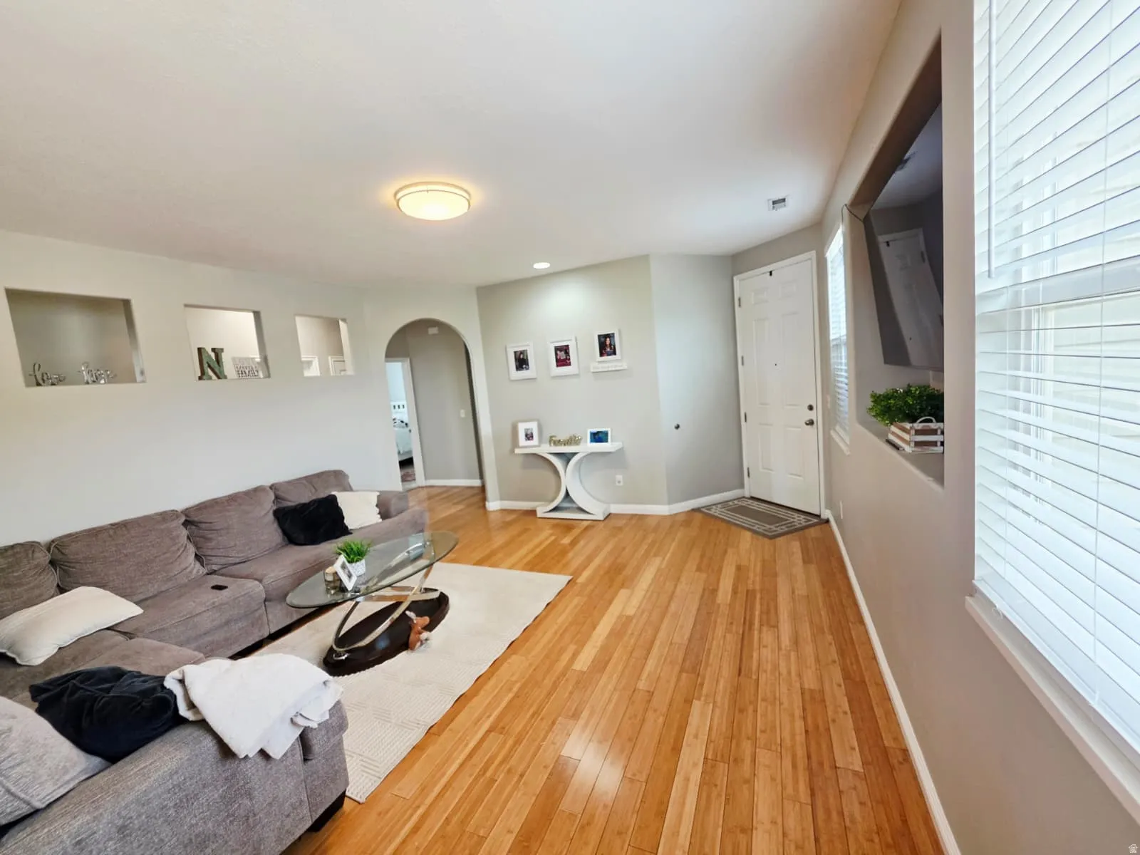 Expansive living area featuring wood-finish flooring, recessed wall niches, and an arched doorway