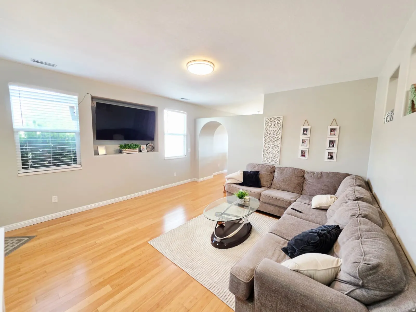 Living room featuring light wood-finish flooring, recessed media niche, arched doorway, and neutral wall tones