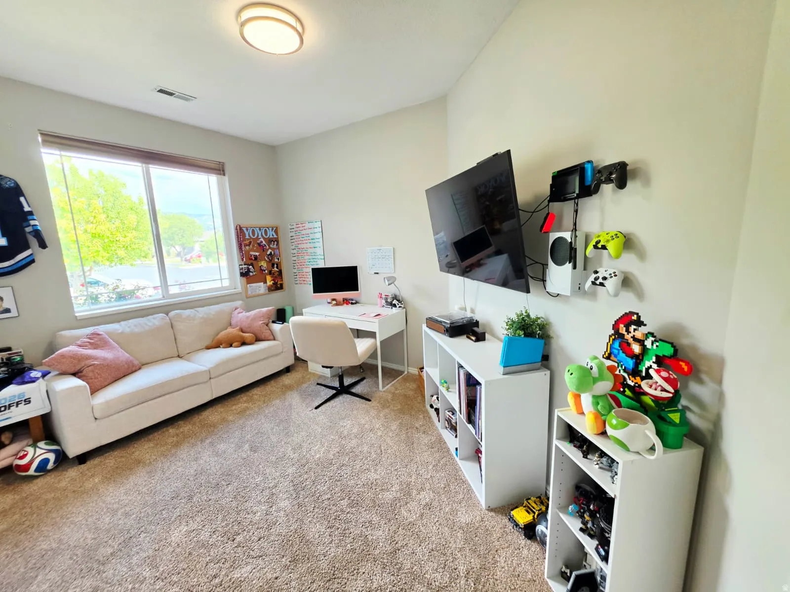 Carpeted room featuring a large window with blinds, a built-in ceiling light fixture, and neutral wall tones