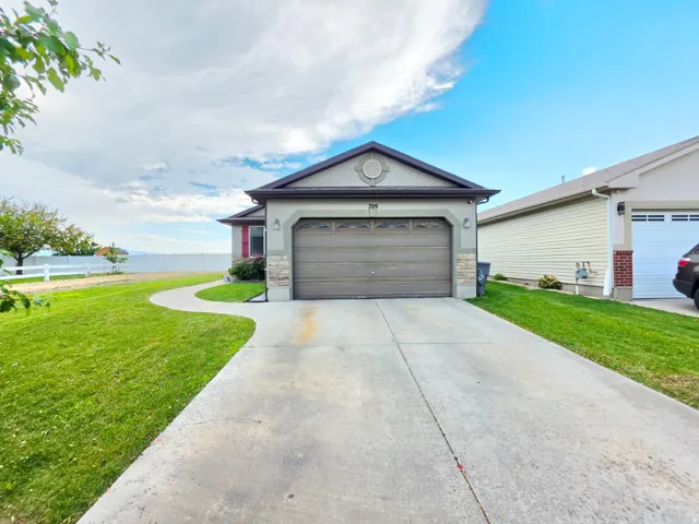 Siding exterior featuring a prominent garage door, stone accents, a concrete driveway, and a curving pathway