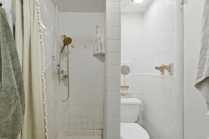 White tile shower stall with a handheld showerhead