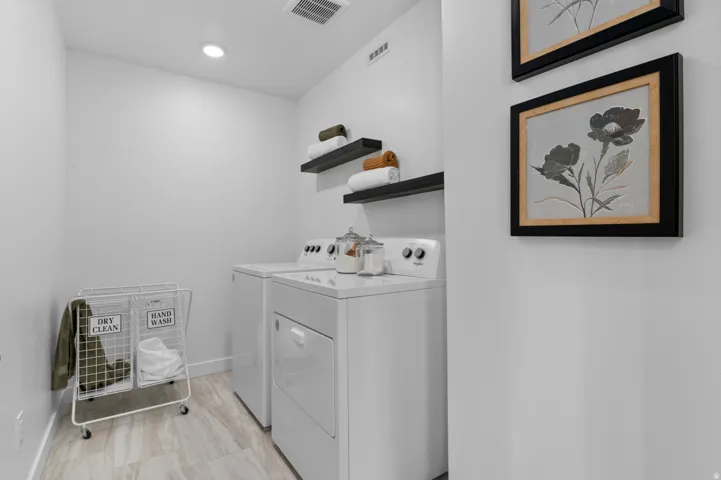 Dedicated laundry area featuring a washer and dryer unit, wood-finish flooring, and recessed ceiling lighting