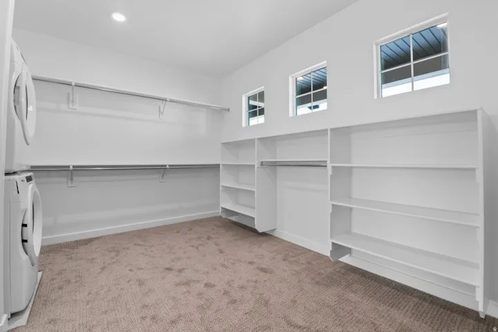 Spacious closet with integrated shelving, hanging rods, and three high-set windows
