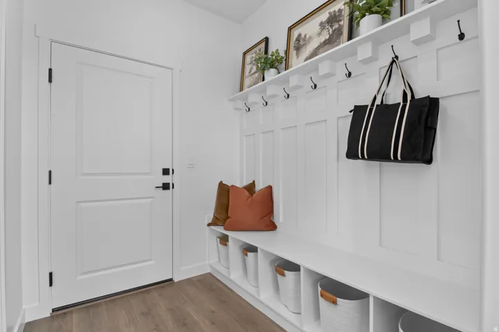 Built-in mudroom bench with cubbies, white paneling, and matte black coat hooks