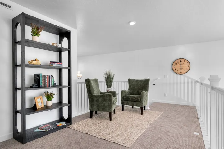 Carpeted upper-level landing featuring white walls, recessed ceiling lighting, and a durable railing system