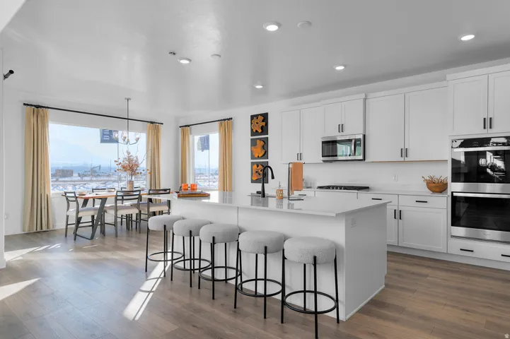 Contemporary kitchen featuring white cabinetry, stainless steel appliances, and a central island with counter seating