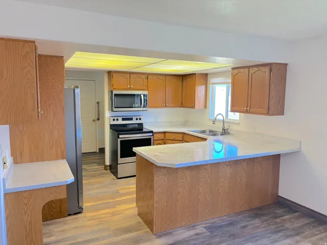 Kitchen featuring wood-finish cabinetry, stainless steel appliances, a breakfast bar, and wood-finish flooring