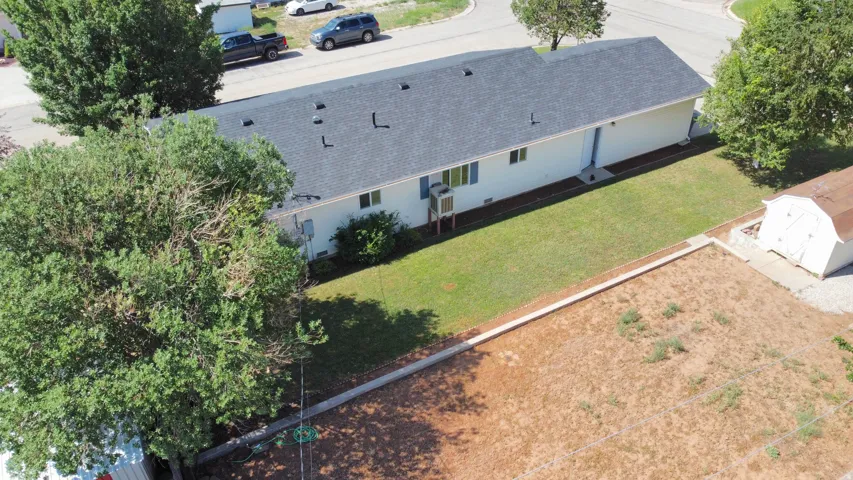Side exterior featuring white siding, a dark shingle roof, and multiple windows with light blue shutters