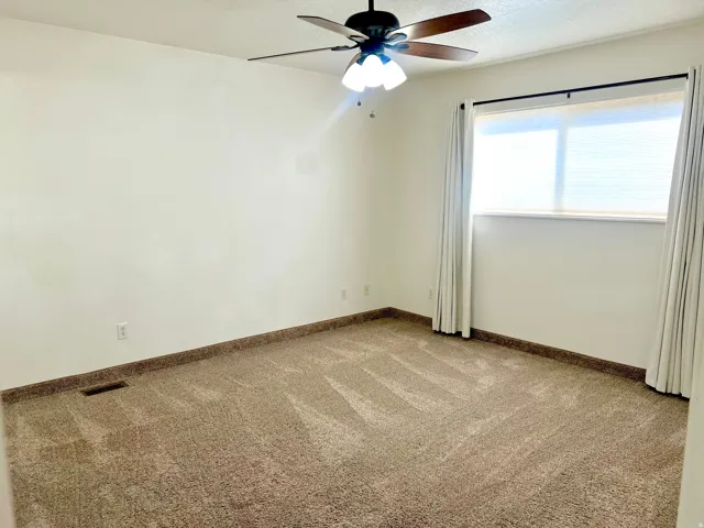 Carpeted room featuring a ceiling fan with integrated lighting, a window with blinds, and accompanying drapery