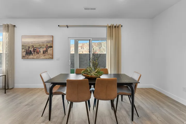 Open-concept living space with light wood-finish flooring, white walls, and a sliding glass door to the exterior