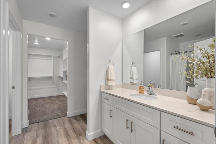 Bathroom vanity featuring a single basin, light-toned countertop, and white cabinetry with brushed nickel hardware