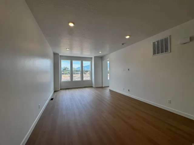 Bright interior space featuring wood-finish flooring, recessed ceiling lighting, and multiple windows