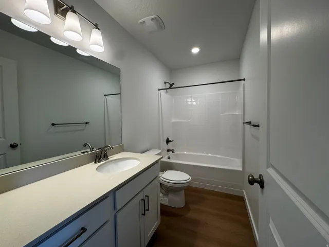 Bathroom featuring a single vanity with light-toned countertop, white cabinetry, undermount sink, and brushed nickel faucet