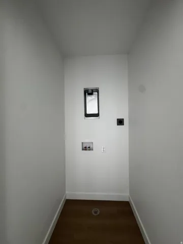 Dedicated utility area featuring wood-finish flooring, white walls, and bright white baseboards