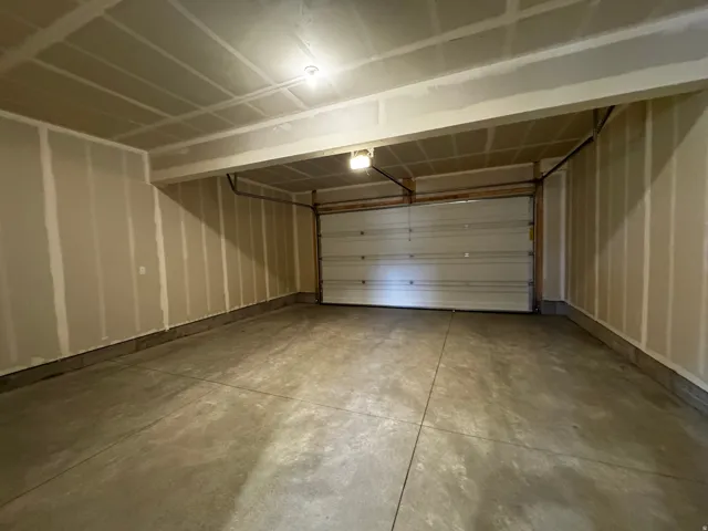 Spacious garage featuring a sectional overhead door, concrete flooring, and exposed ceiling joists