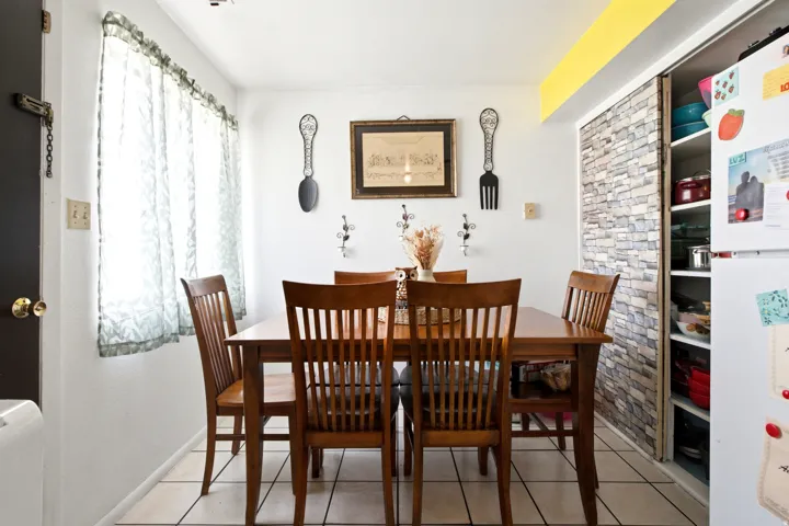 Dining area featuring tile flooring, a window with natural light, and a built-in storage closet with a stone-look facade