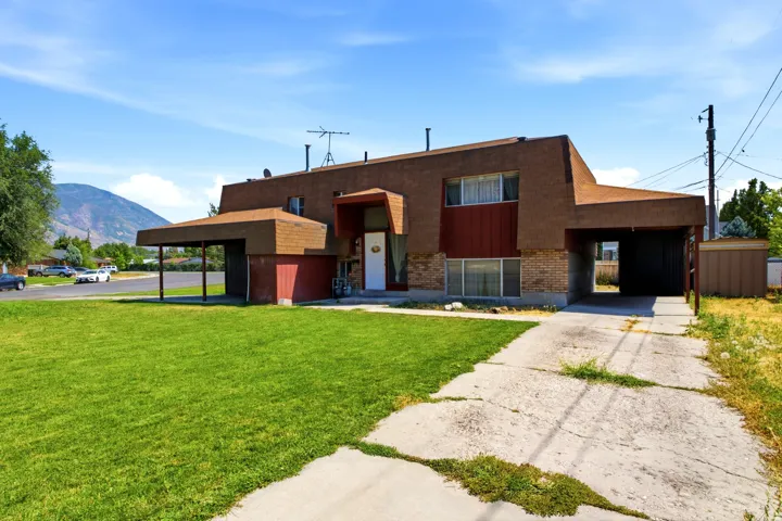 Multi-level residence featuring a brick facade, covered entry, and two integrated carports